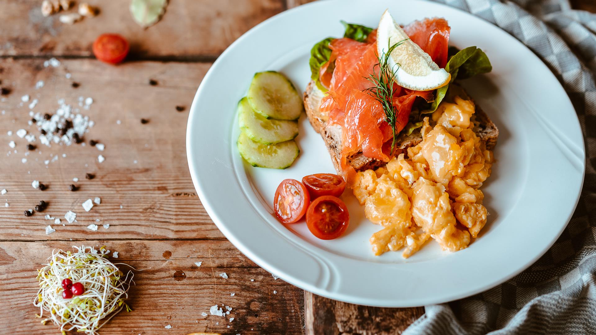 Plate of salmon with roasted potatoes and fresh salad vegetables on a wooden table