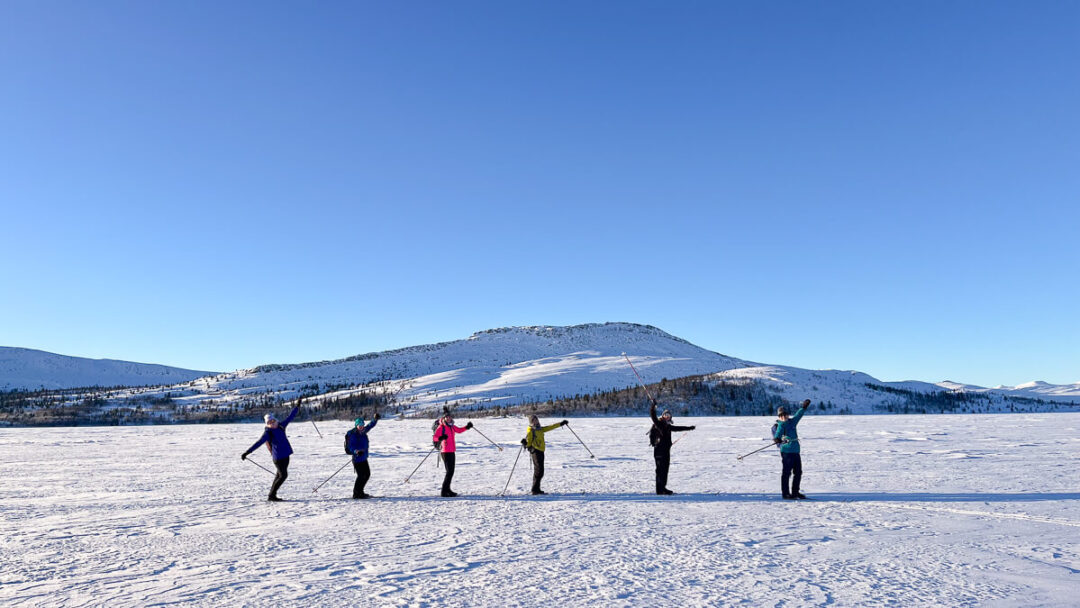 Women practising yoga on a snowy winter landscape in Norway under a clear blue sky