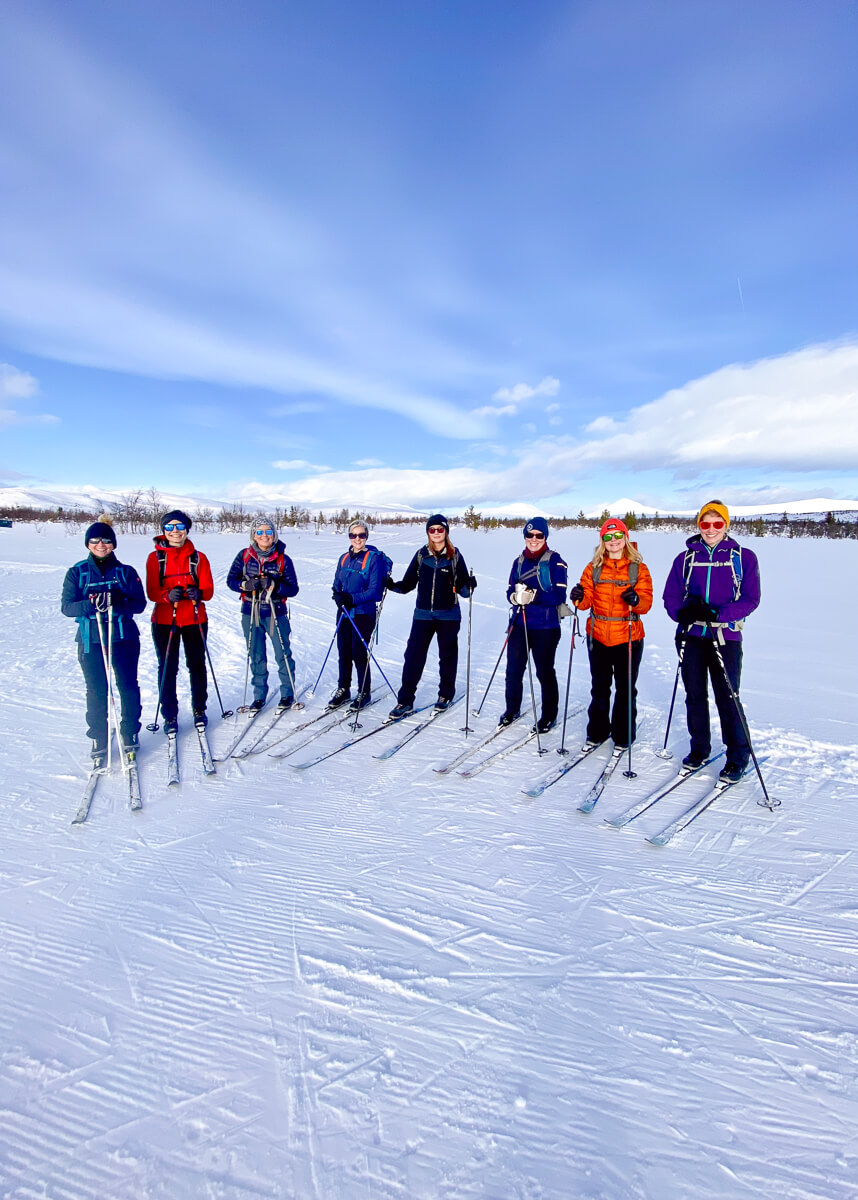 Women cross-country skiing on a snowy landscape under a blue sky