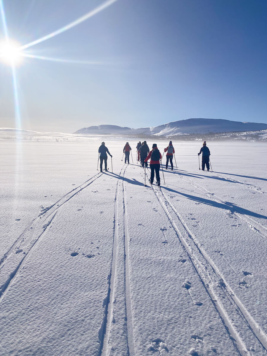 Women cross-country skiing on a snowy trail in Norway under clear winter skies