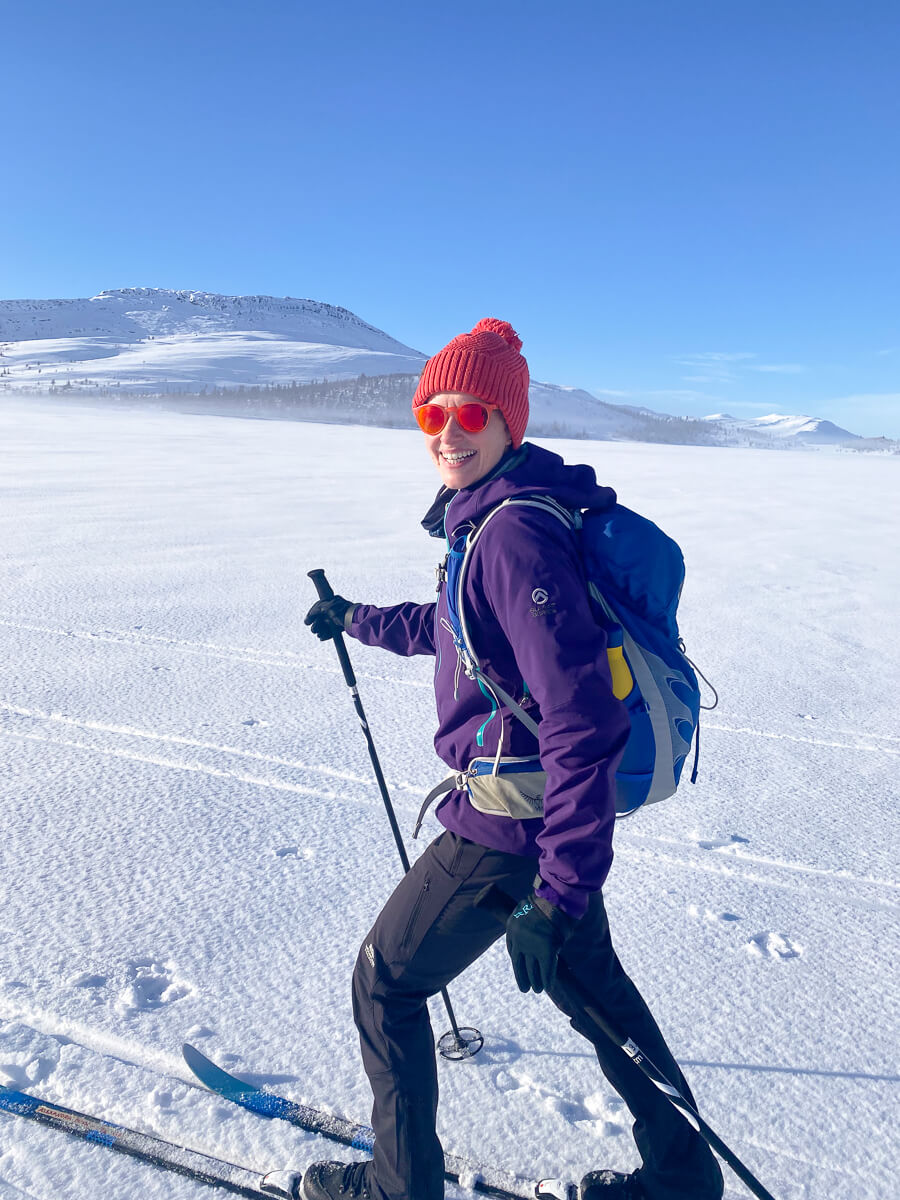 Woman cross-country skiing on a snowy trail through mountain landscape in winter