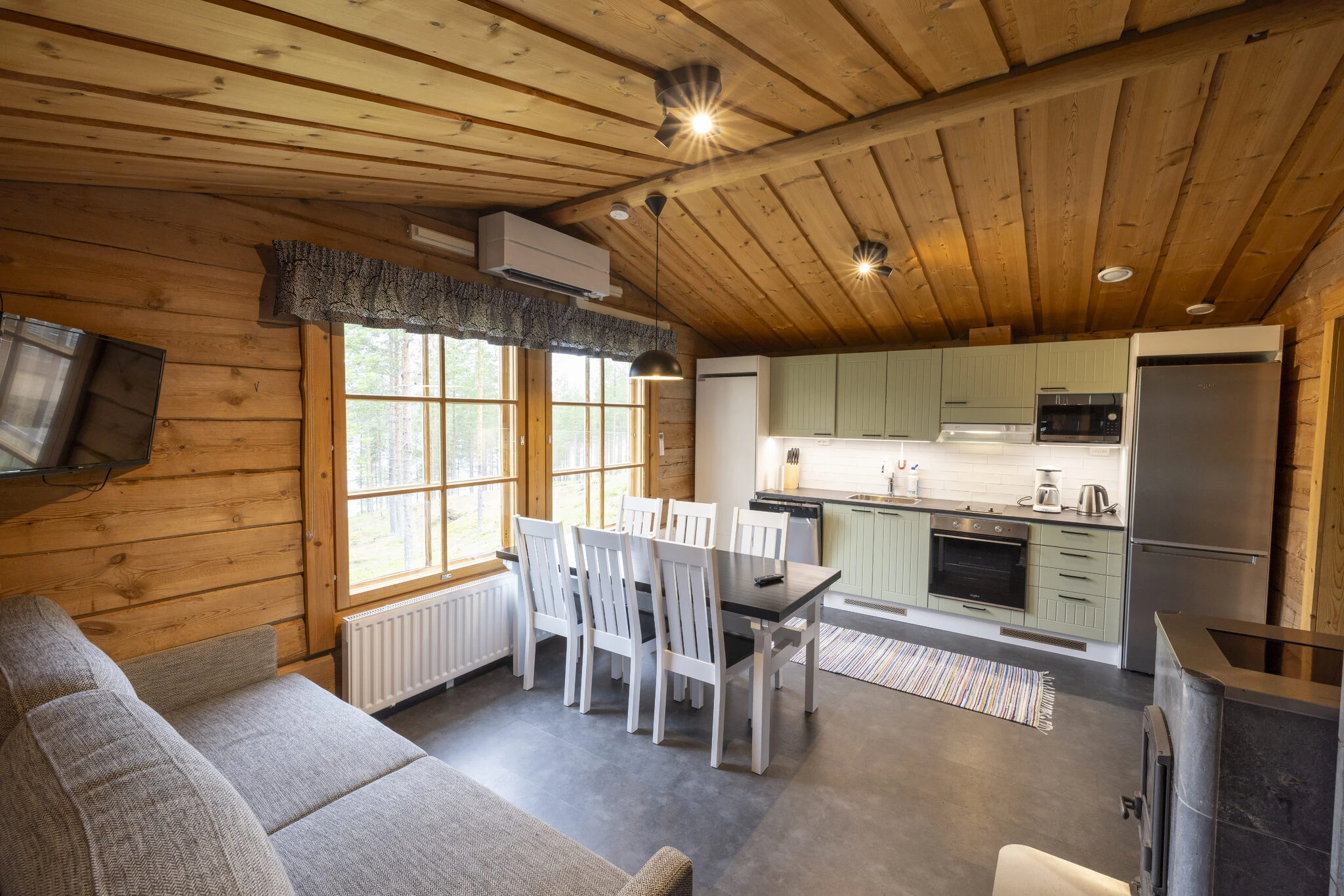 Wooden cabin lounge with sofa, dining table and kitchen area