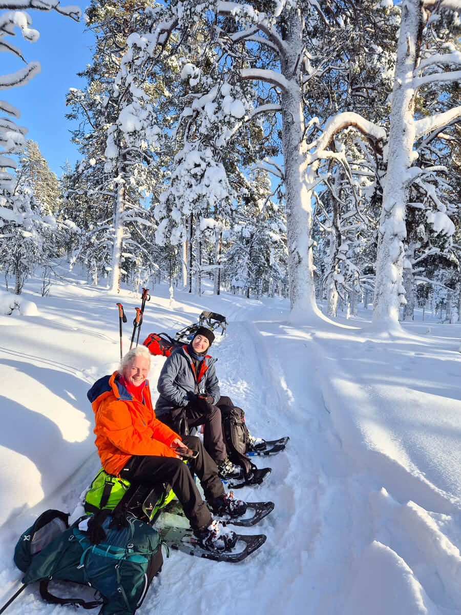 Two women on skis in a snowy forest, Lapland backcountry ski trail