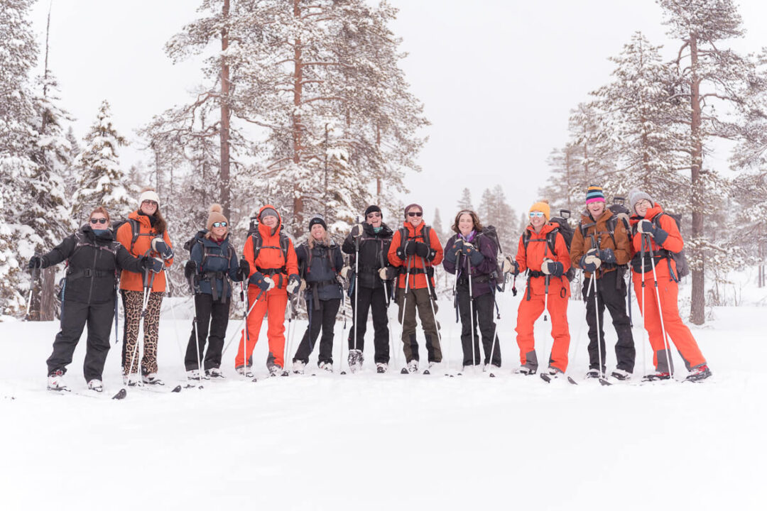 Women backcountry skiers standing in snowy forest with skis and winter gear, winter expedition