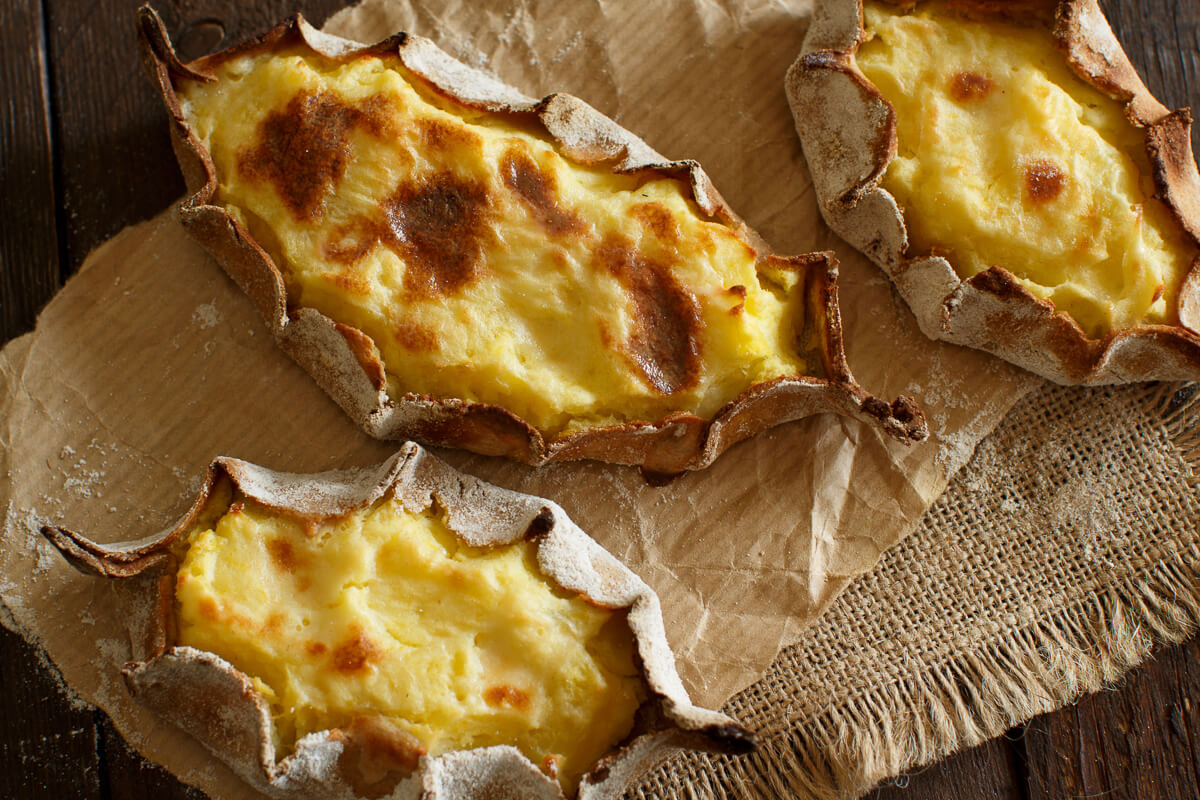 Crispy cheese pastries torn open on baking paper on a wooden table