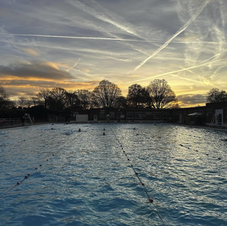 Outdoor swimming pool at sunset with lane ropes and clear water in a leisure centre