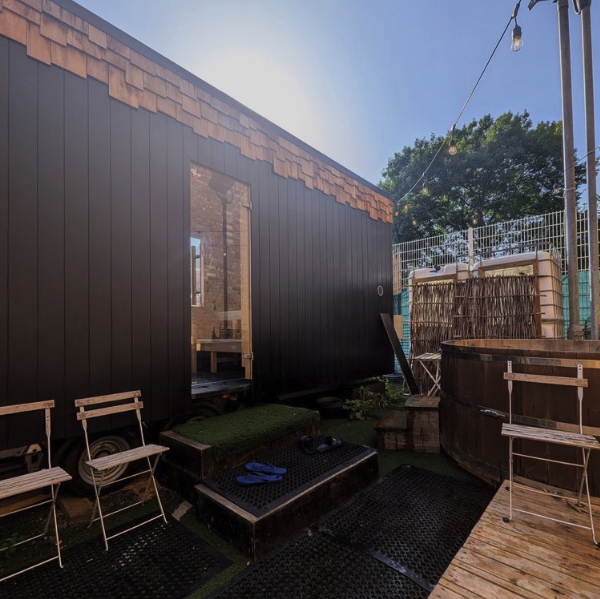 Outdoor sauna cabin with wooden hot tub and benches in a garden courtyard