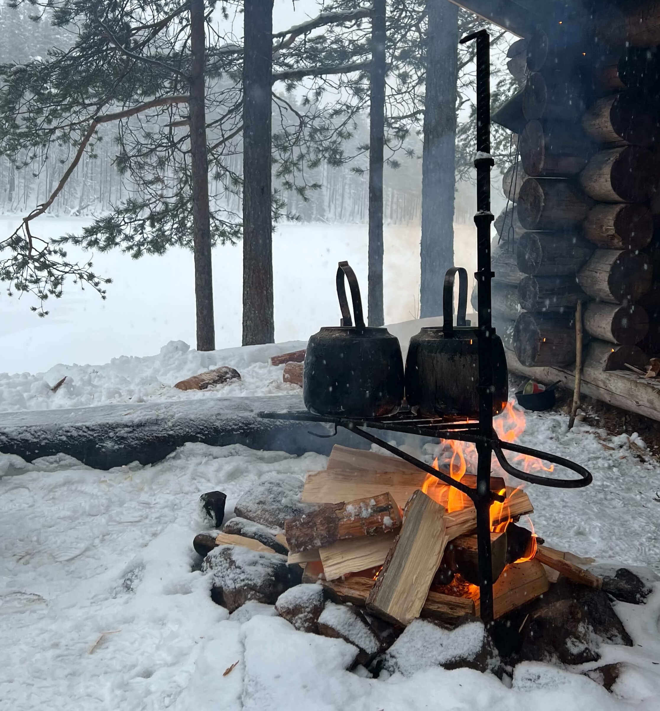 Wood-burning stove with kettles in a snowy cabin forest during cross-country ski in Finland
