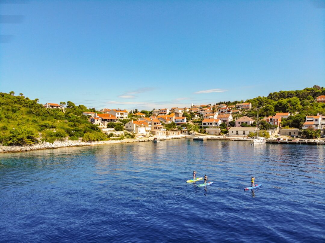 Women paddleboarding off a coastal town near Zadar, Croatia, on calm blue sea