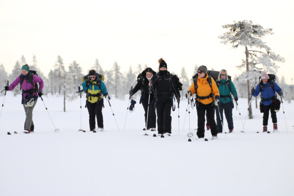 Women backcountry skiing through snowy forest in Sweden