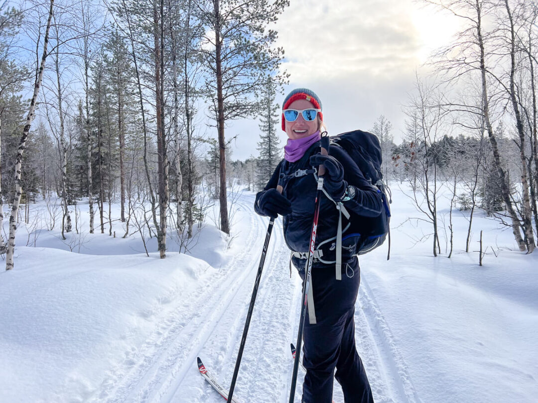 Woman cross-country skiing on a snowy trail through a winter forest