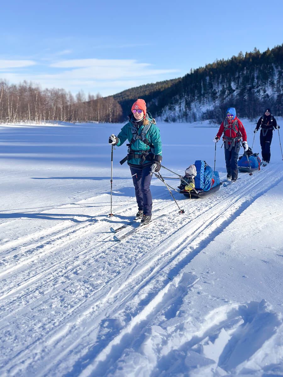 Women cross-country skiing on a snowy trail through a winter forest landscape
