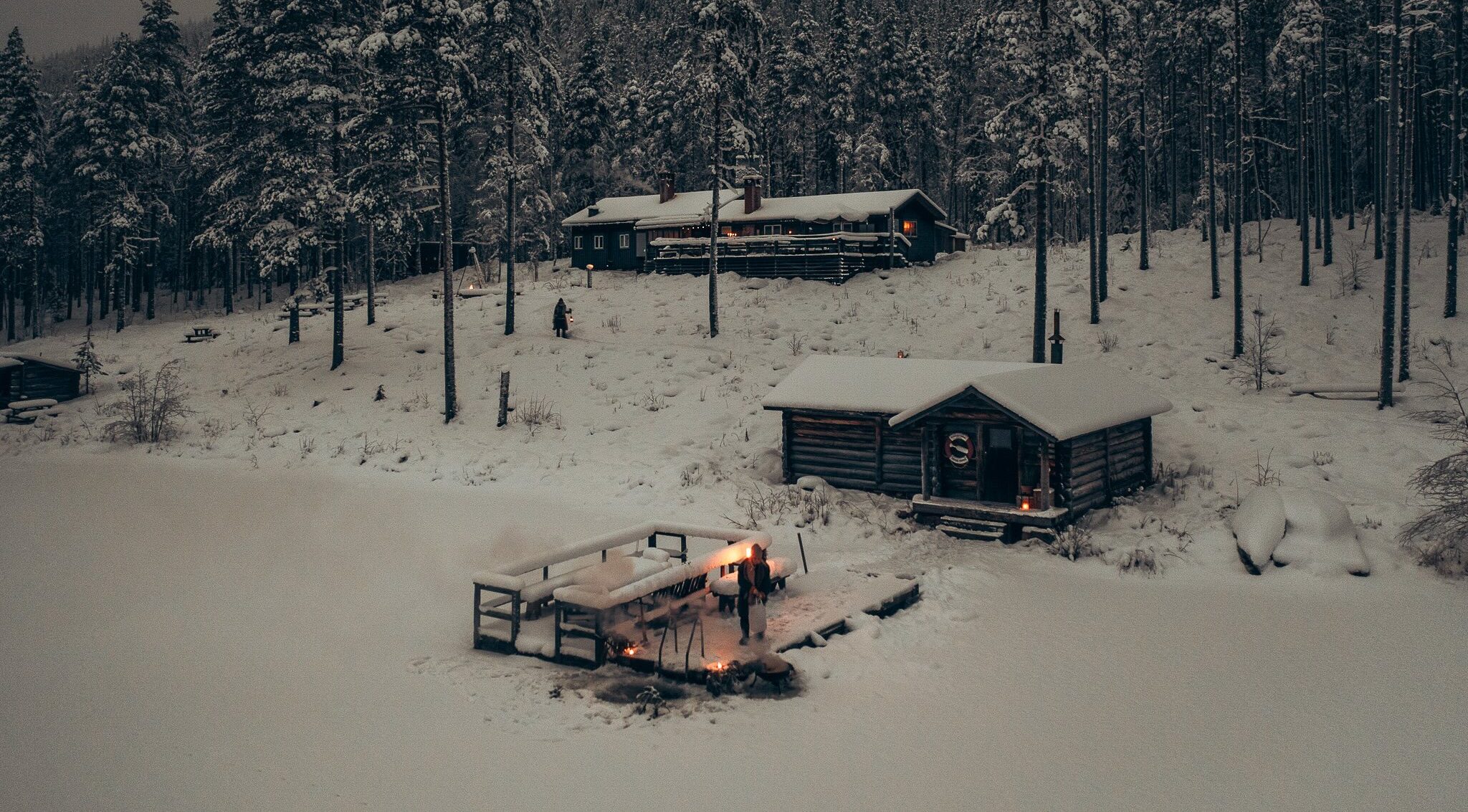 Snowy winter camping huts in a forest clearing at a backcountry camp in Sweden