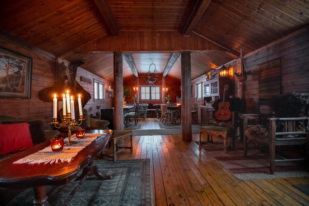 Cozy wooden cabin interior with lit candles, dining table and chairs, winter camping shelter ambience