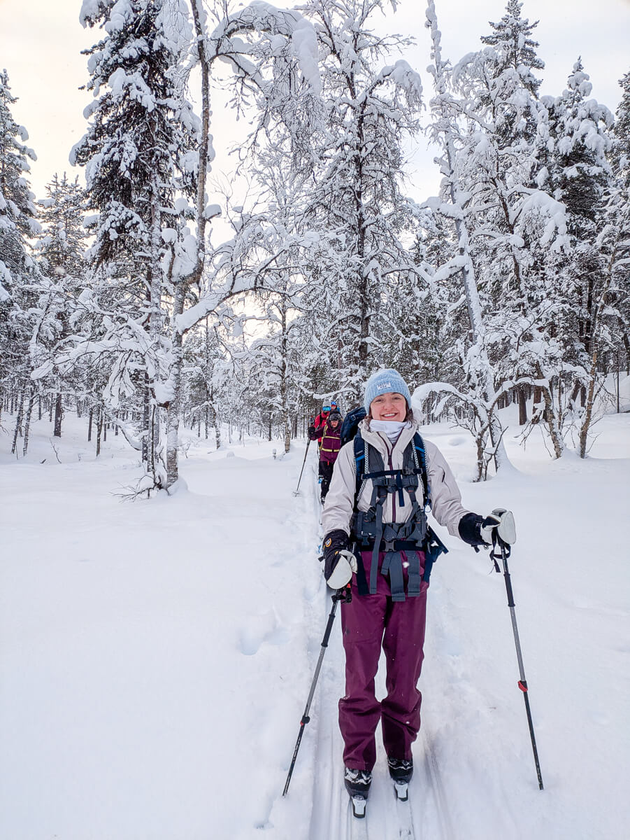 Woman cross-country skiing through a snowy forest with trekking poles in winter conditions