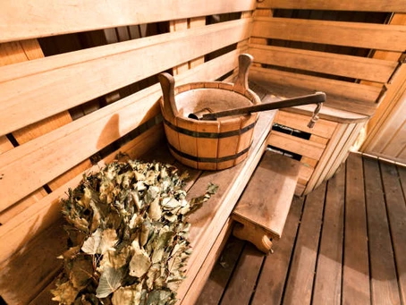 Wooden sauna interior with birch leaf whisk and water bucket for steam bathing