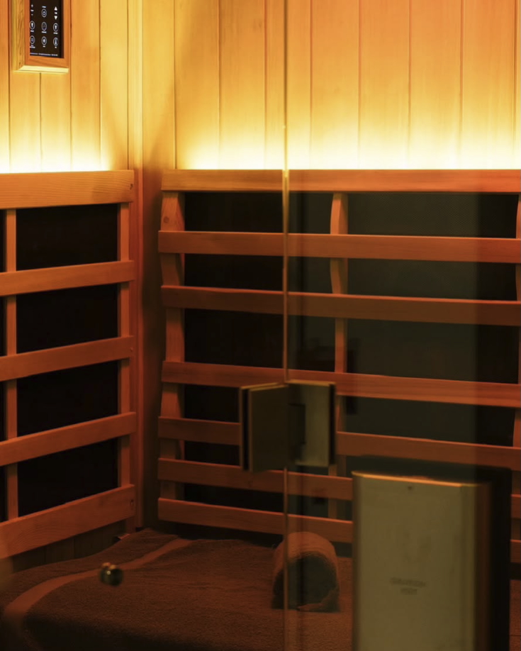 Wood-lined sauna interior with wooden benches and warm amber lighting, showing the steam-room style.