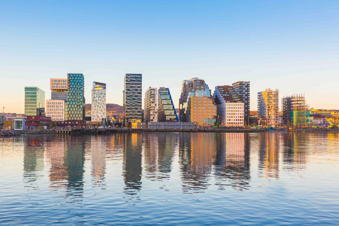 Oslo skyline along the waterfront at dusk, reflected in calm water