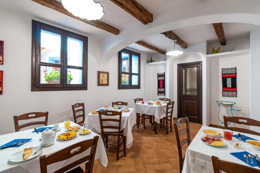 Sunlit dining room with set tables, wooden beams and framed windows