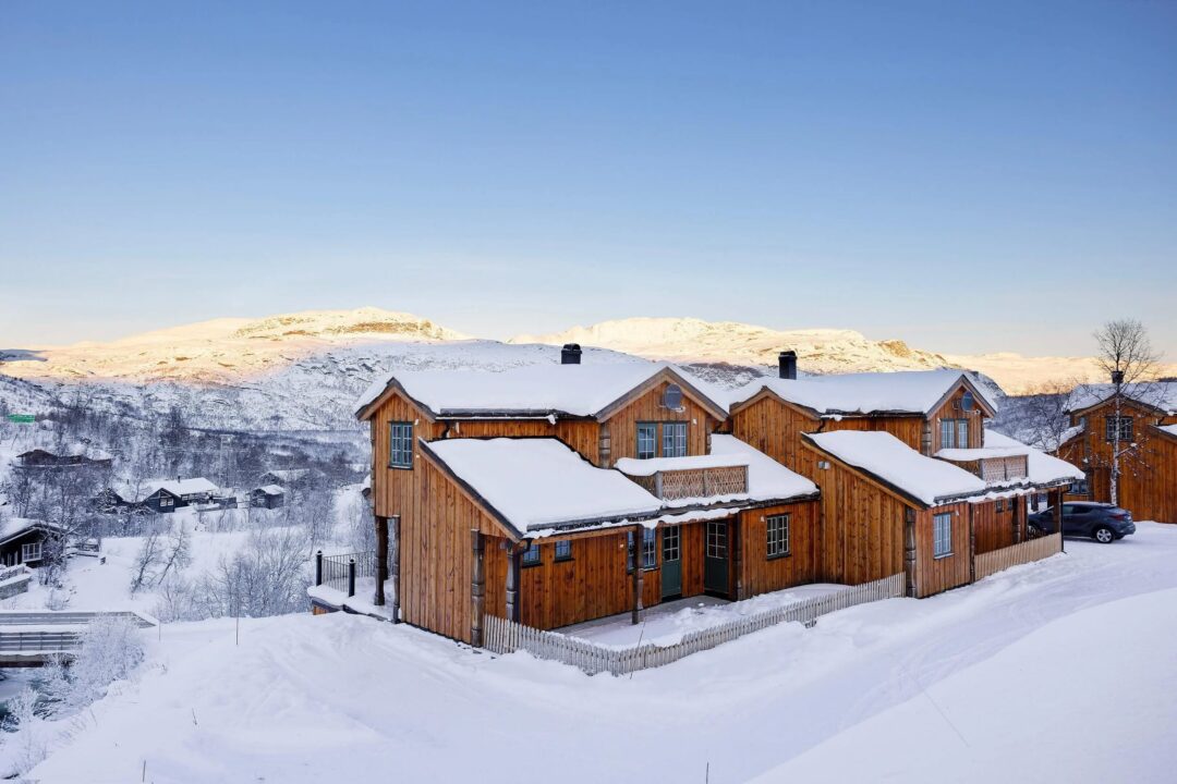Snowy wooden cabins in a winter landscape in Norway, under a clear blue sky