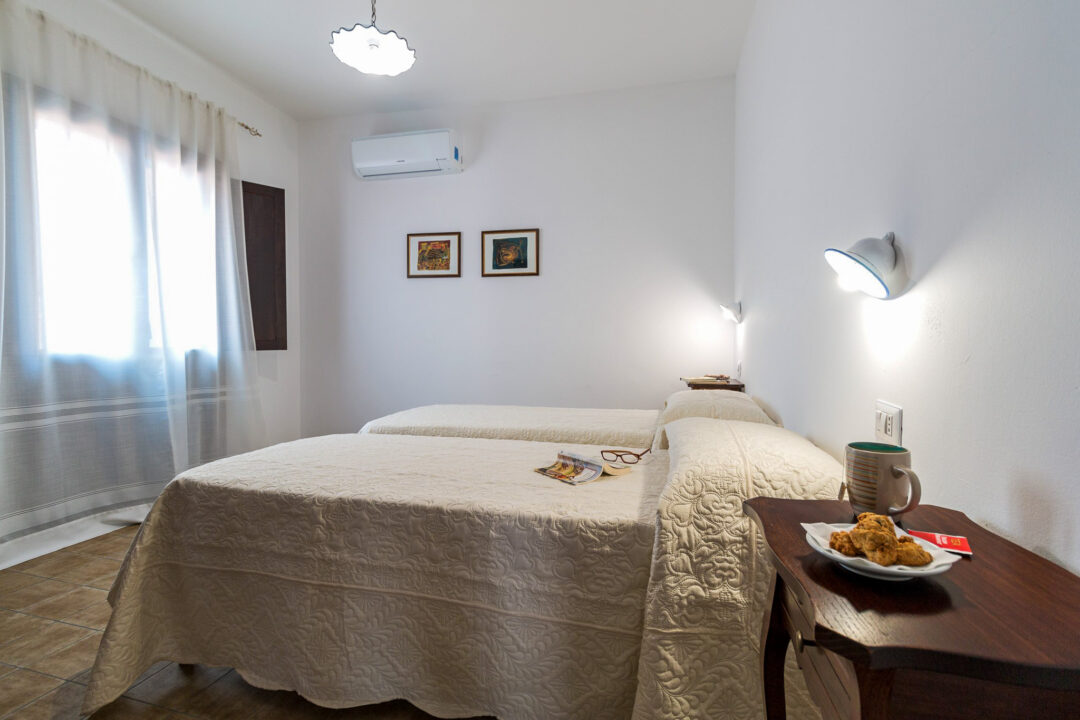 Sunlit bedroom with double bed, bedside table and lamp in a home interior