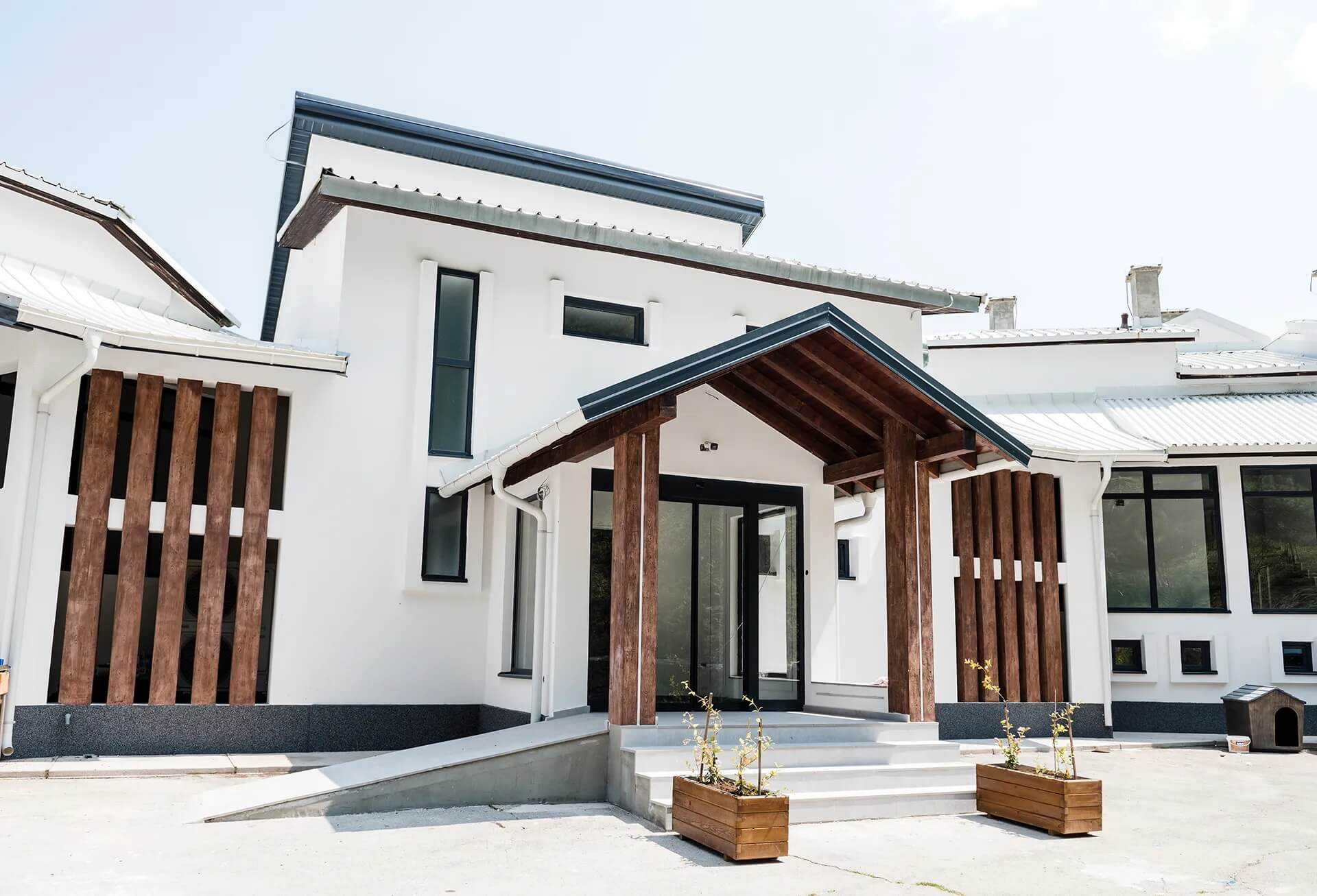 Modern white holiday house exterior with wooden porch and small courtyard patio