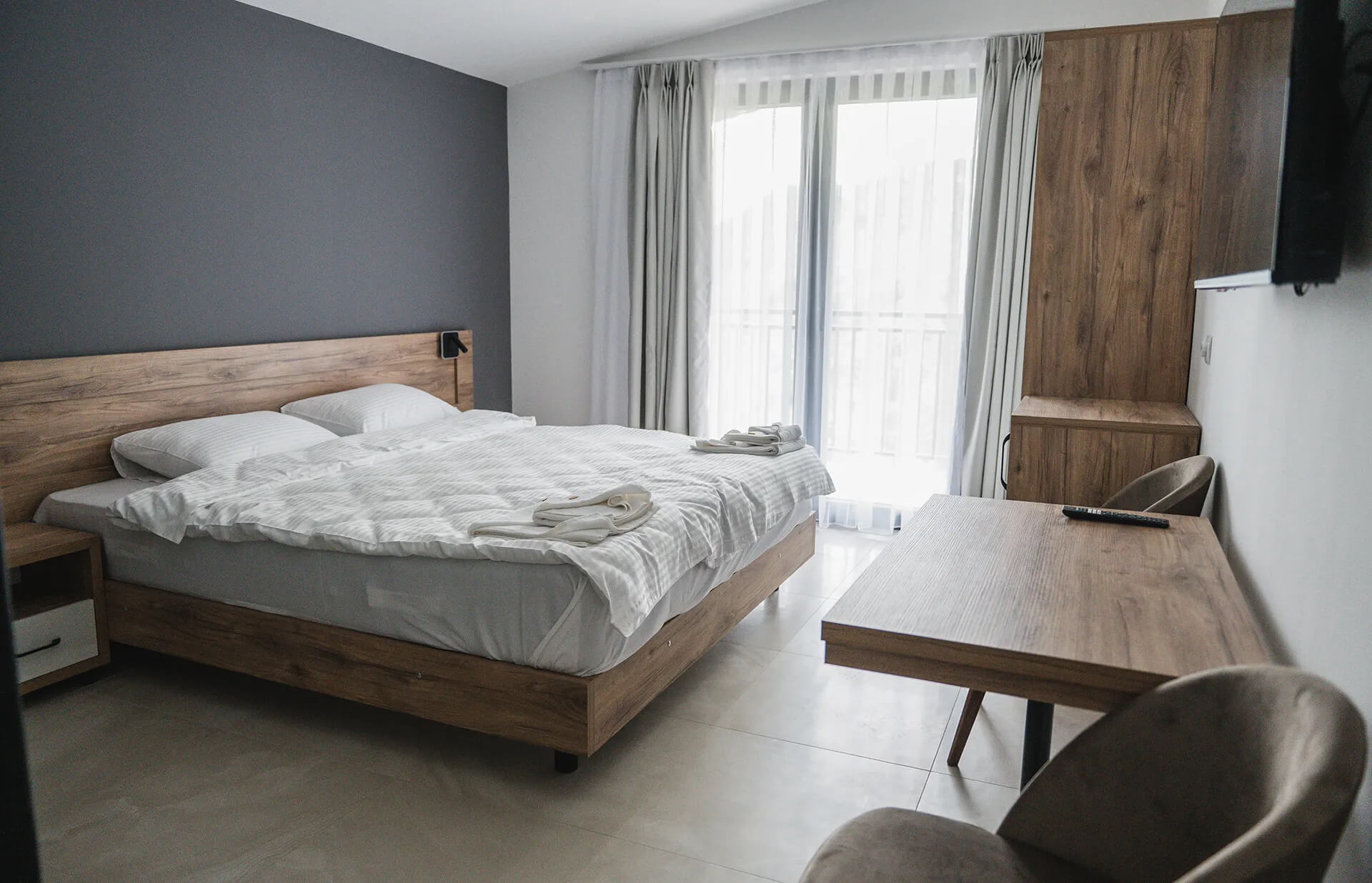 Modern hotel bedroom with double bed, seating area and French doors to a balcony, Lake Ohrid holiday base
