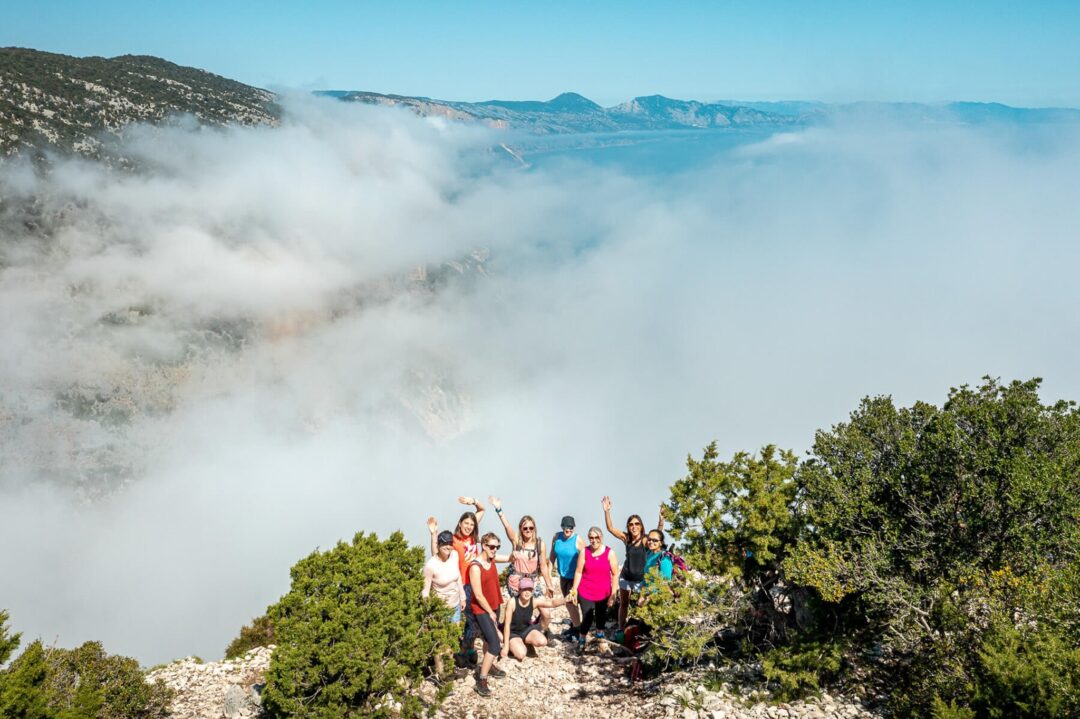 Women hikers stand on a rocky ridge above sea fog on a mountain trail in coastal scenery
