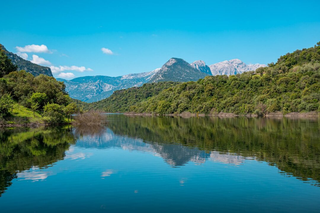 Sardinia east coast coastal hike view over a calm lake with mountains and blue sky