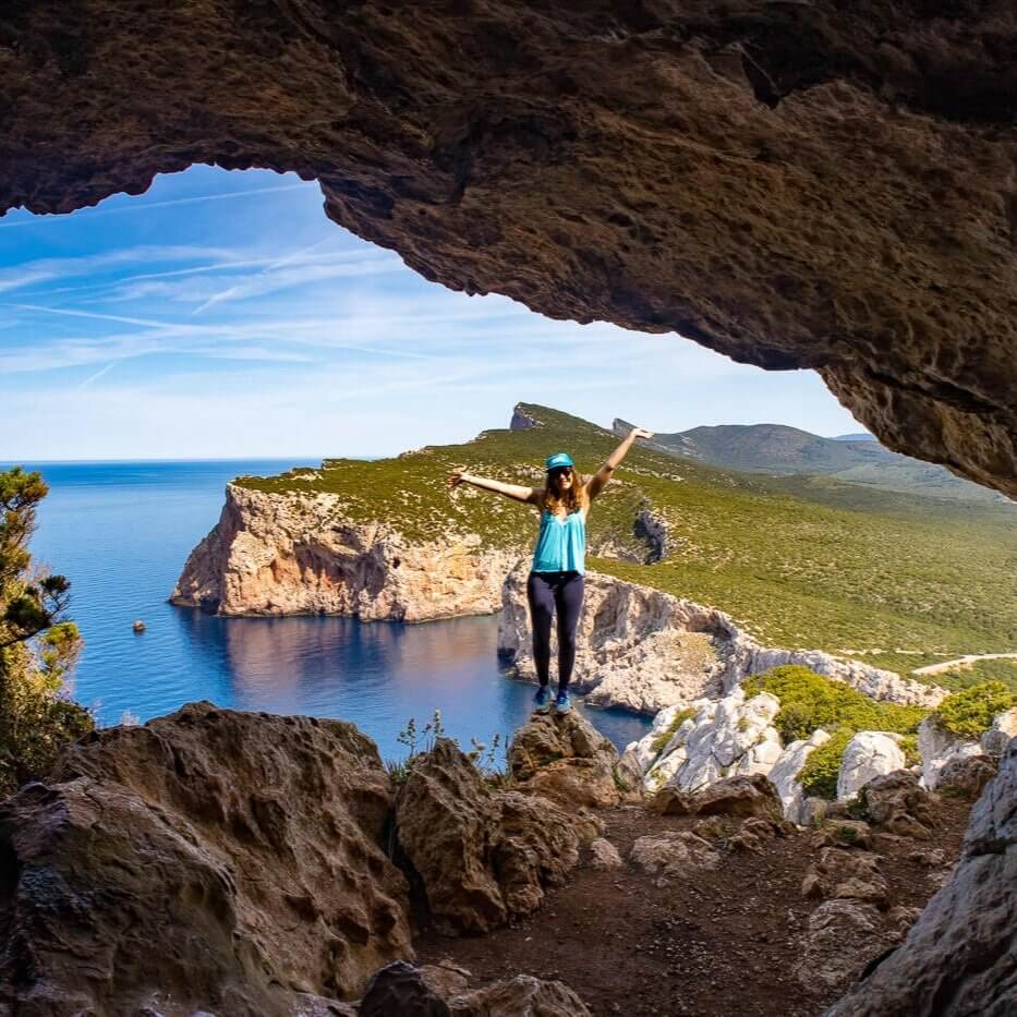 Woman performs a yoga stretch on a sea cliff rock overlooking blue water and coastline