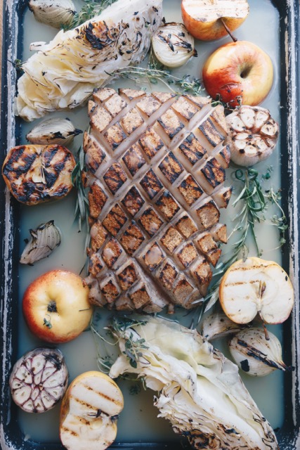 Tray of winter grilled fish, sliced apples and herbs, suggesting a Lapland outdoor cooking meal