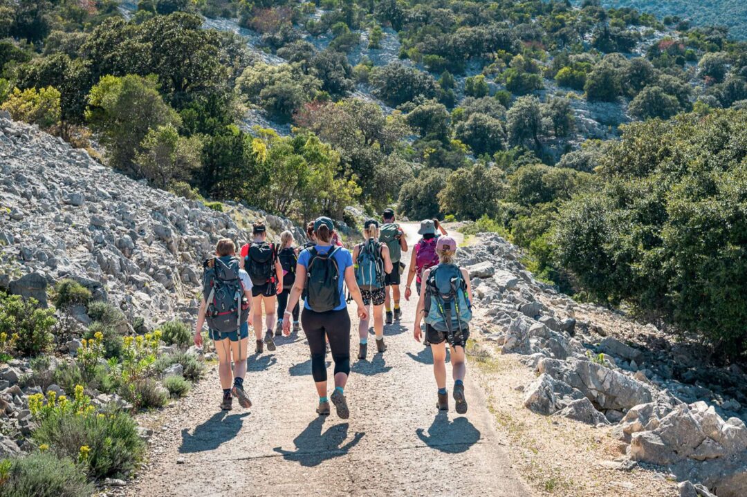 Women hiking along a rocky trail through lush green hills