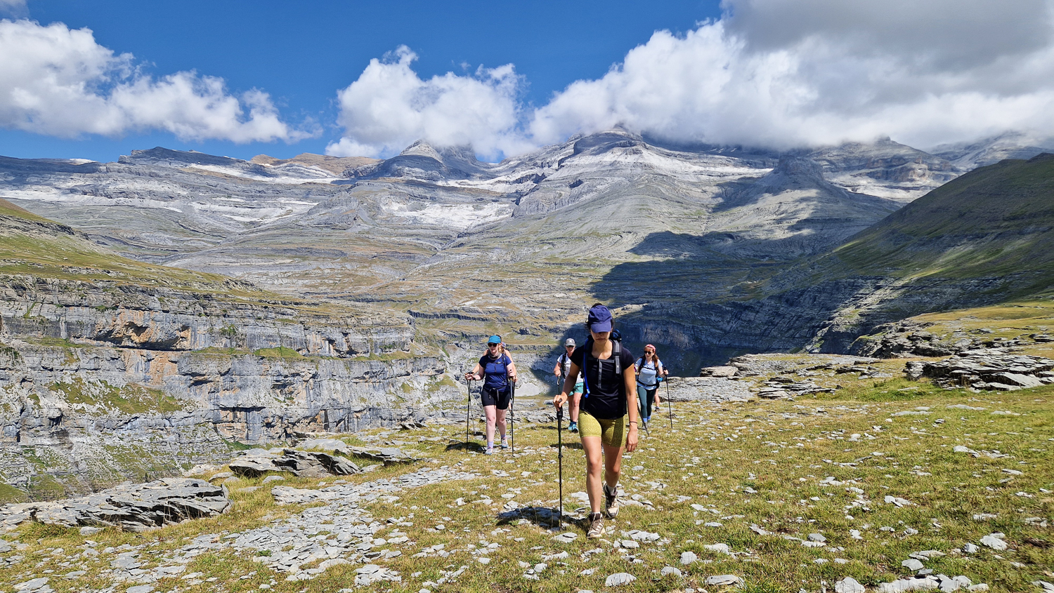 Women hiking on a mountain trail in the Spanish Pyrenees with rocky landscape and distant peaks