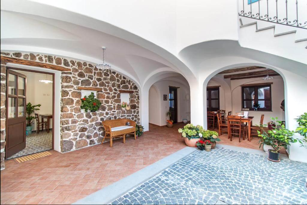 Stone-arched courtyard with a small swimming pool, outdoor seating and potted plants