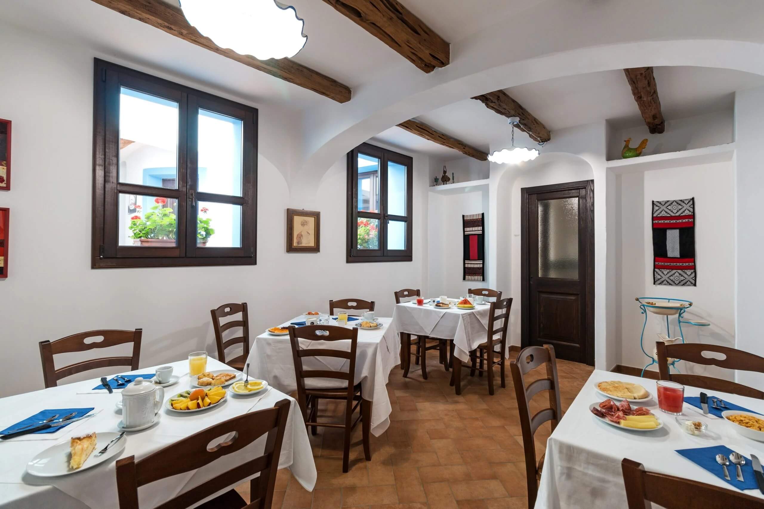 Light, rustic dining room with set tables and wooden beams, for a Kayak, Hike and eBike adventure stay