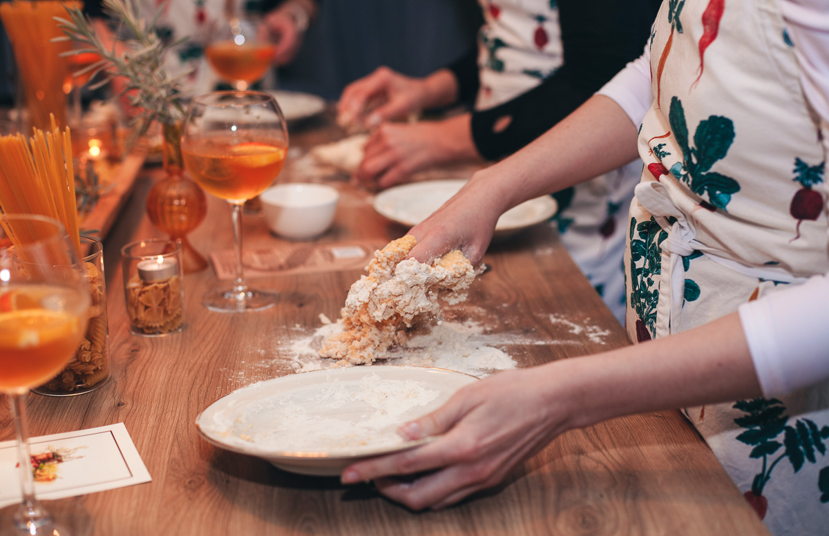 Women preparing dough together at a table during a relaxed meal in Sardinia adventure weekend