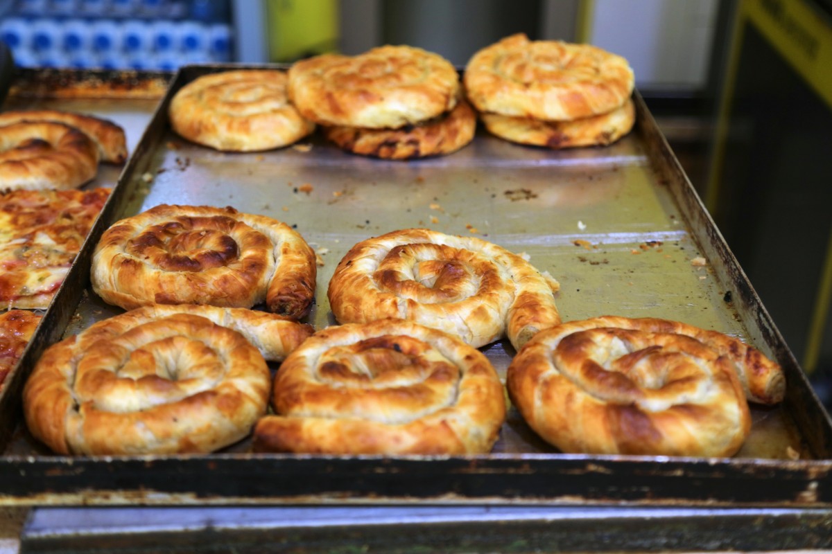 Tray of freshly baked pastries in an oven, with golden-brown flatbreads cooling on metal baking sheets