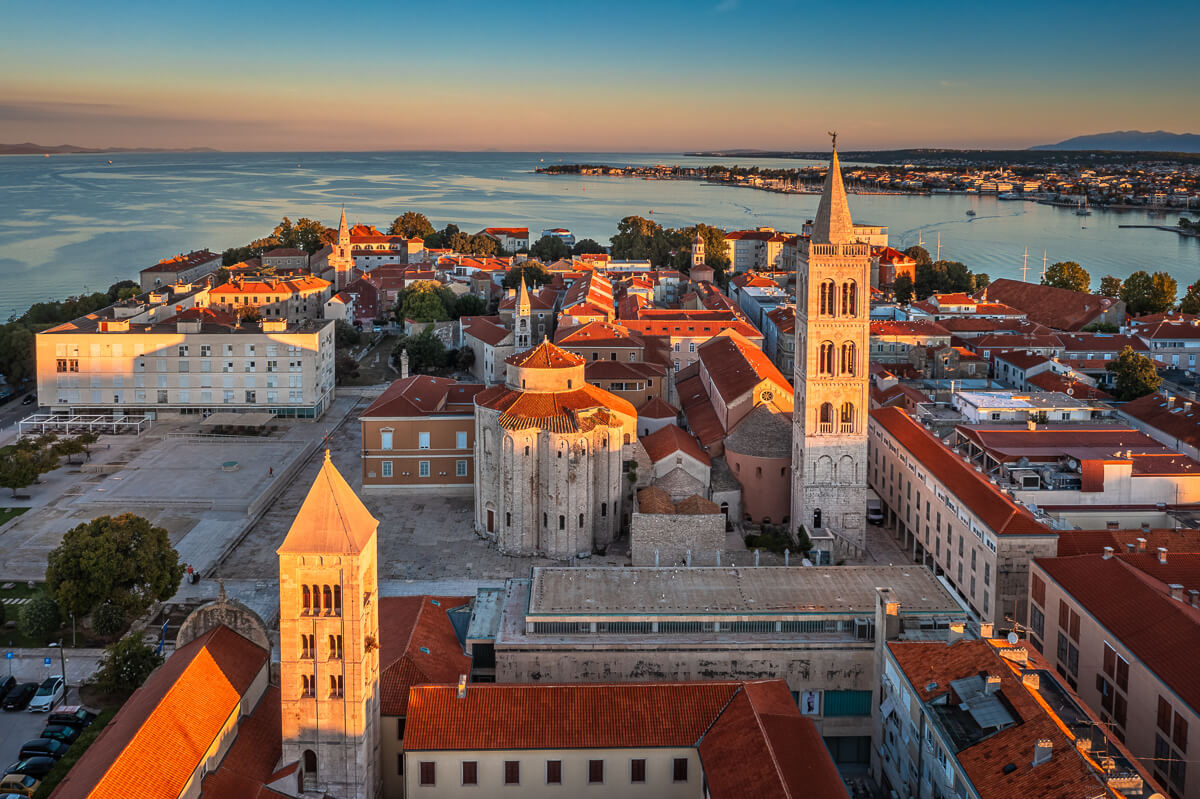 Aerial view of a Croatian coastal town with church and marina at dusk