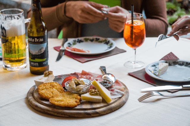 Dining table with schnitzel, antipasti, bread and glasses of beer and wine on a covered spread