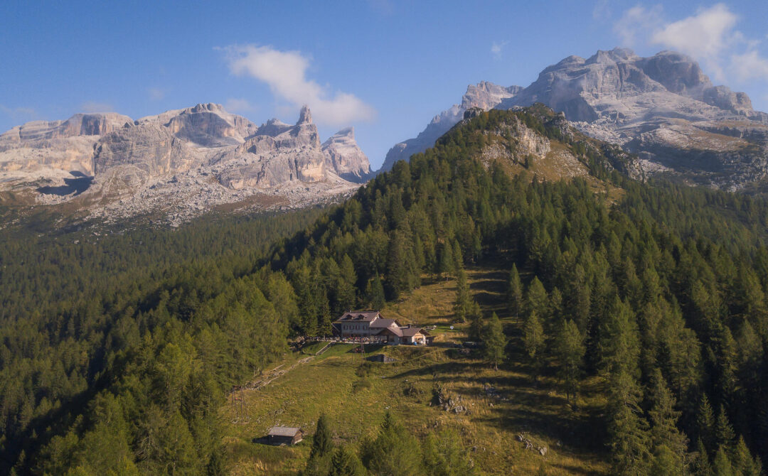 Dolomites alpine landscape with forested slopes and mountain huts, set in Italy’s Dolomite mountains