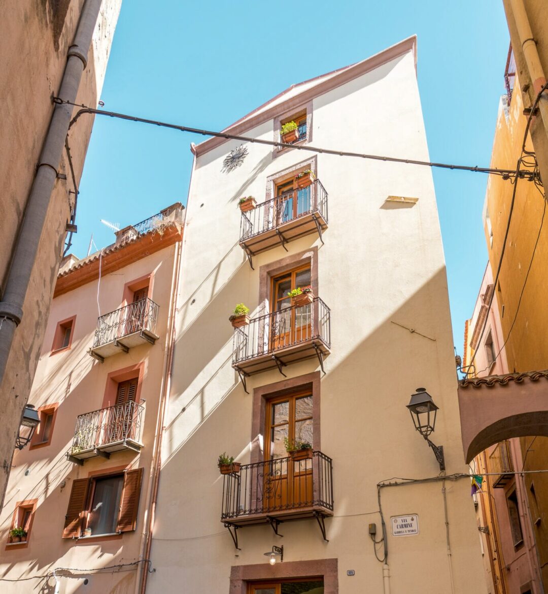 Sunlit narrow street with pastel apartment buildings in Sardinia, Italy