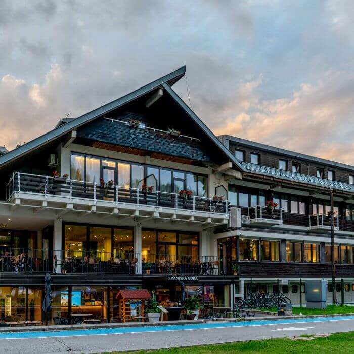 Modern resort hotel exterior with balconies and outdoor swimming pool at dusk