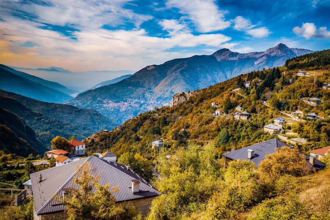 Mountain valley with forest slopes and a hillside village at sunset, scenic for hiking in North Macedonia