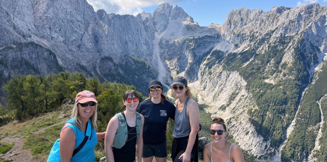 Women hiking at a mountain viewpoint with rocky peaks in the background