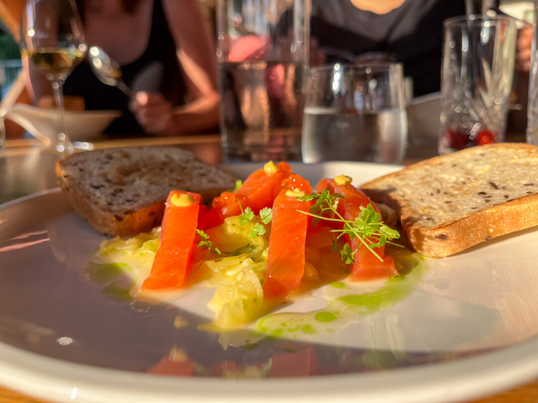 Plate of gourmet seafood starter with salmon, herbs and greens on a restaurant table
