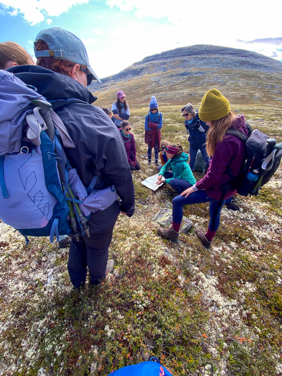 Women hikers in Norway mountains, sitting on a hillside and stretching during a break