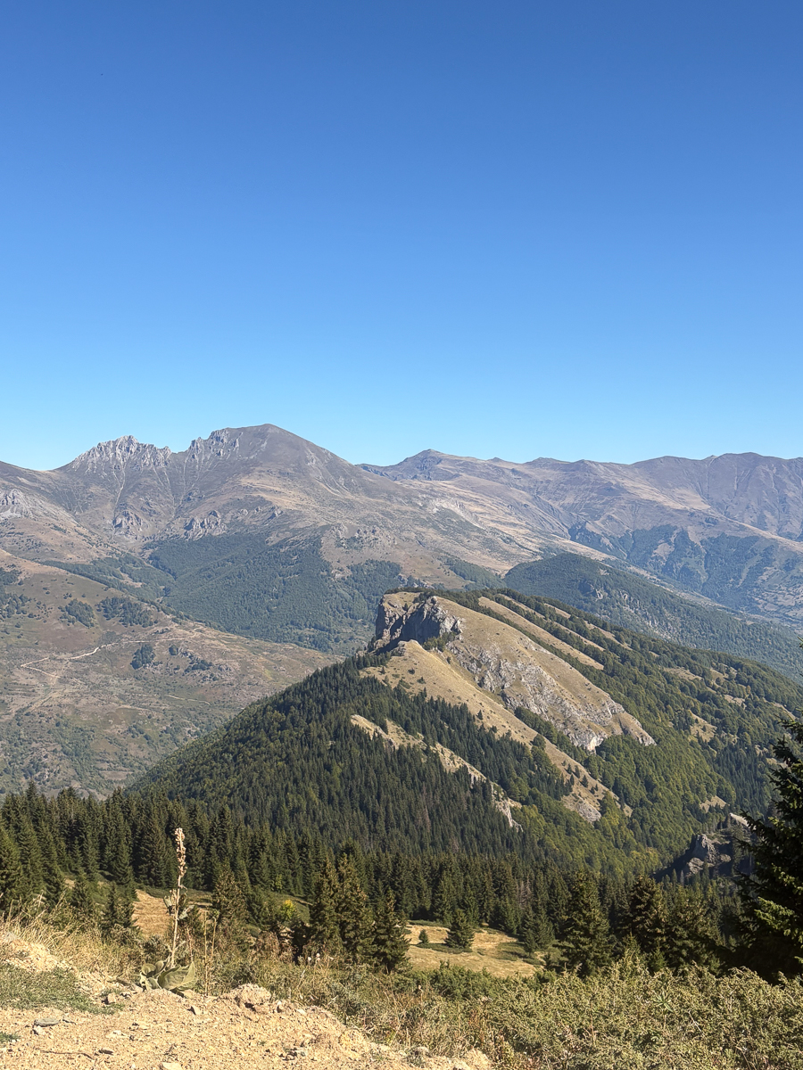 Hiking trail through a rugged mountain valley and peaks under a clear blue sky