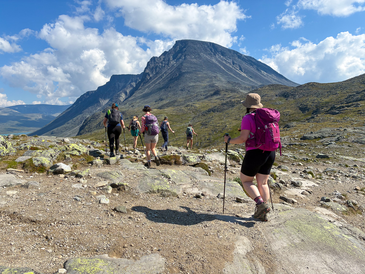 Women hiking on a mountain trail with backpacks in Norway’s alpine landscape