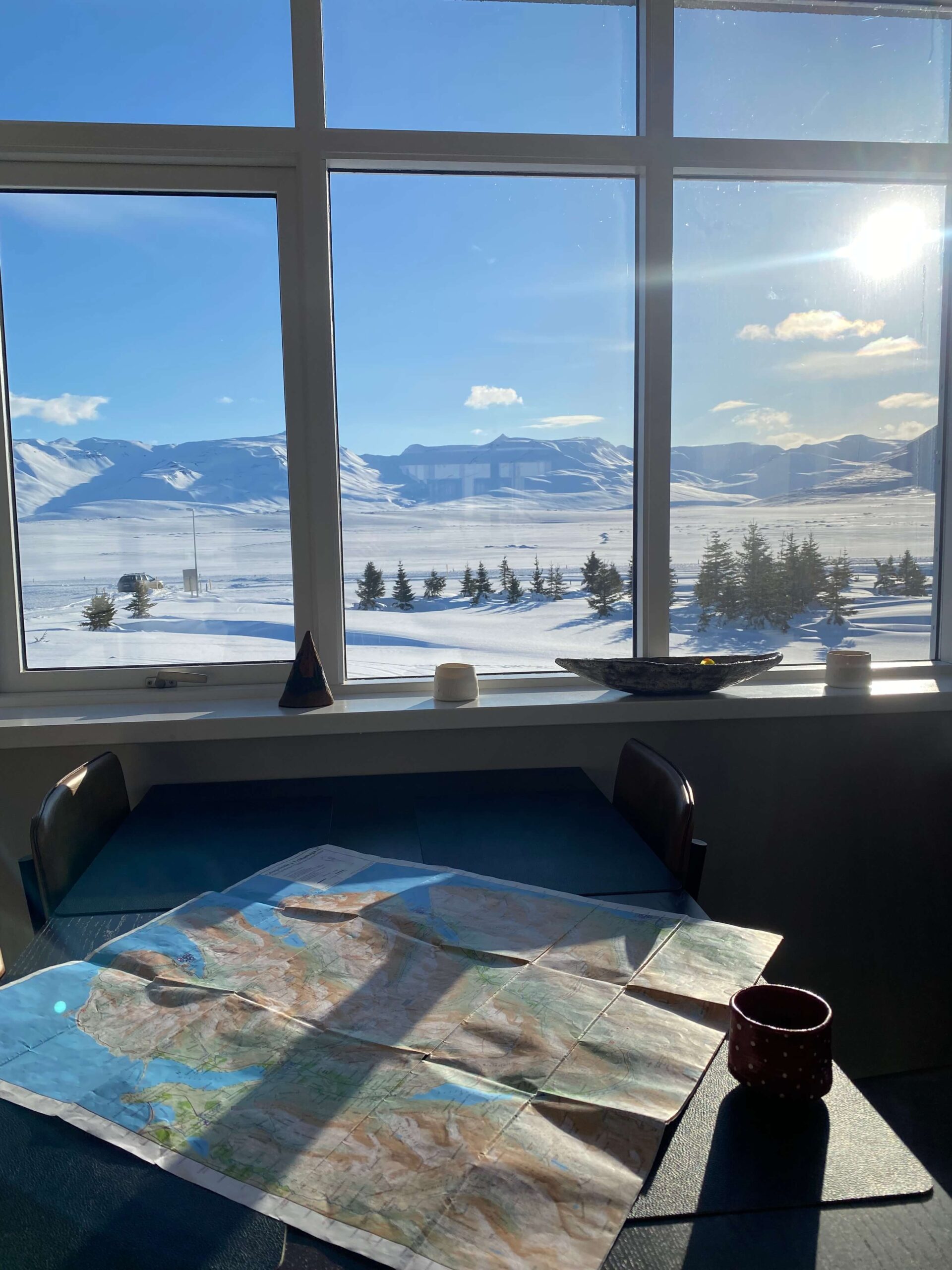 Snowy North Iceland landscape seen through a window from a table with a map and mug