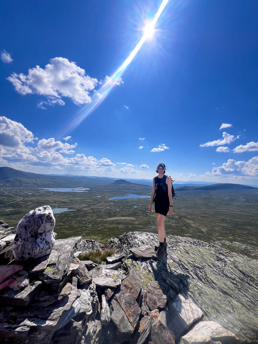 Women hiking on a rocky summit with lake and valley views over Norway under a blue sky